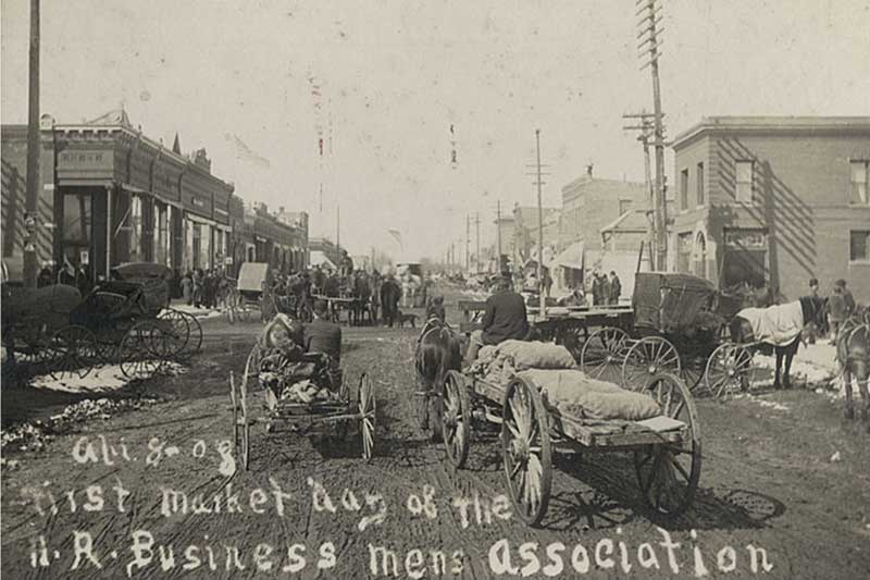 old black & white photo of people on horses pulling carts